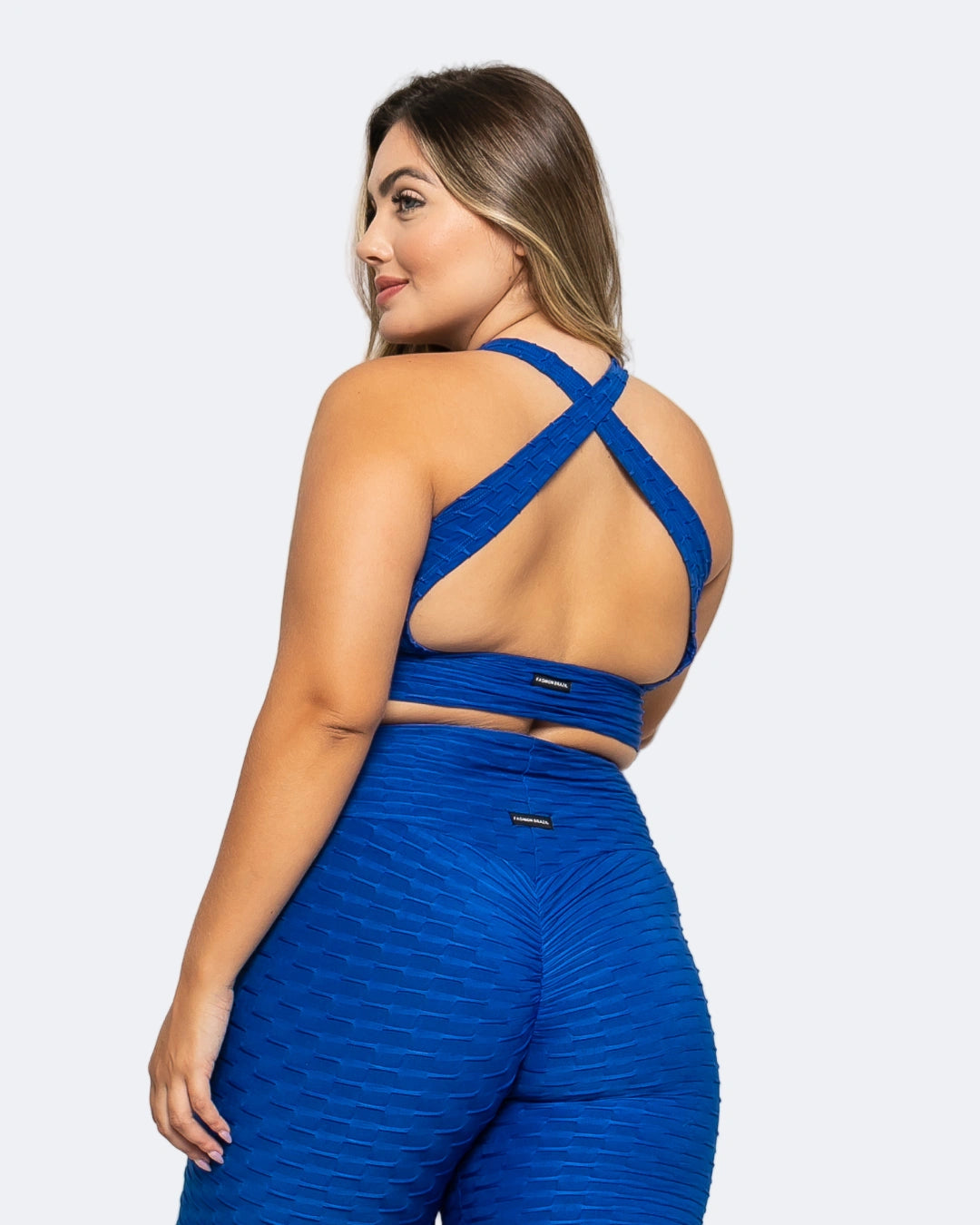 Woman wearing a blue sports bra and leggings set against a light gray background