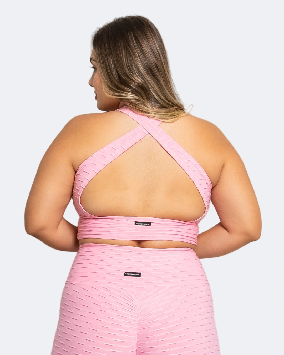 Woman wearing a pink sports bra and leggings set on a white background