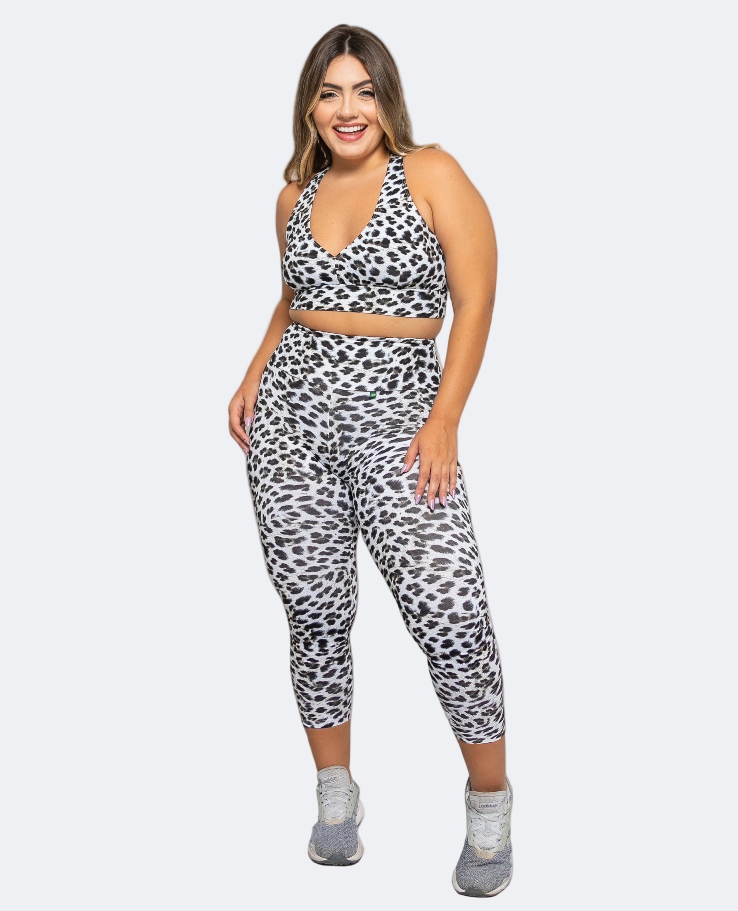 Woman wearing a leopard print sports bra and leggings set against a white background
