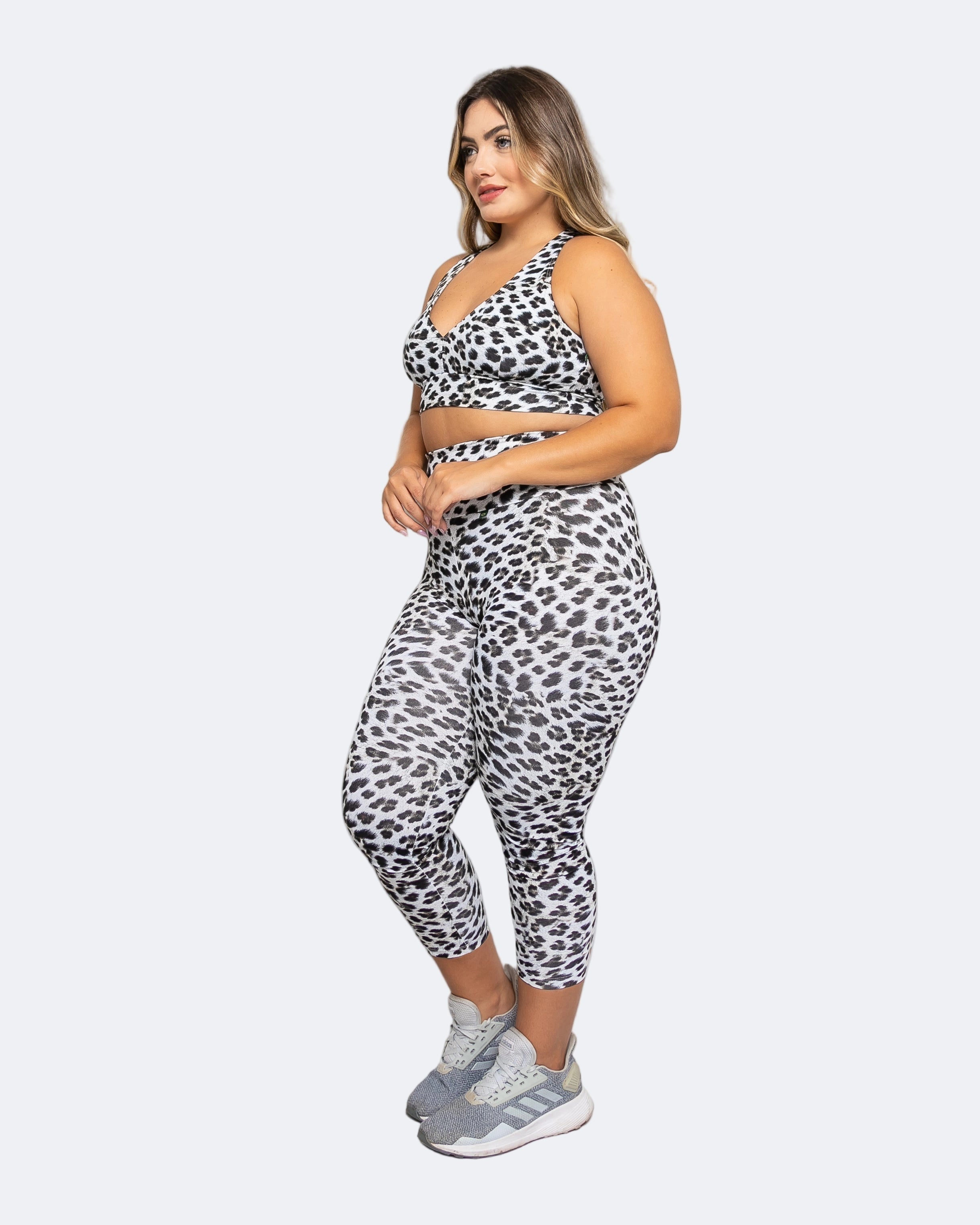 Woman wearing a leopard print sports bra and leggings set on a white background