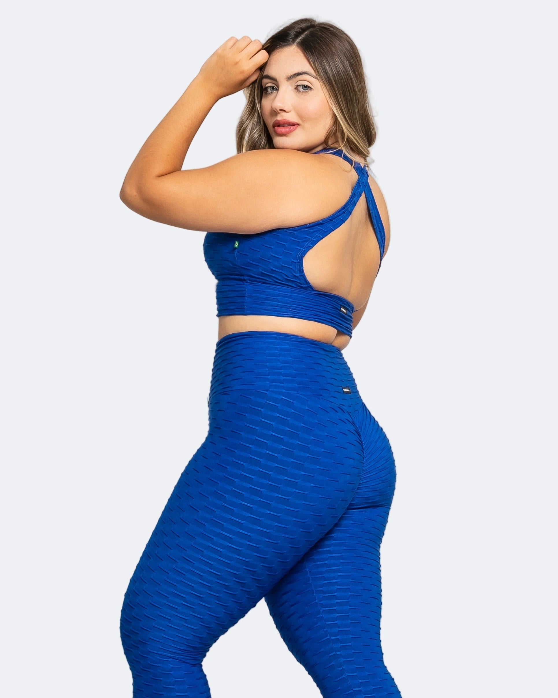 Model wearing Fashion Brazil blue high-waisted scrunch booty legging and a matching sports bra, standing against a plain background.