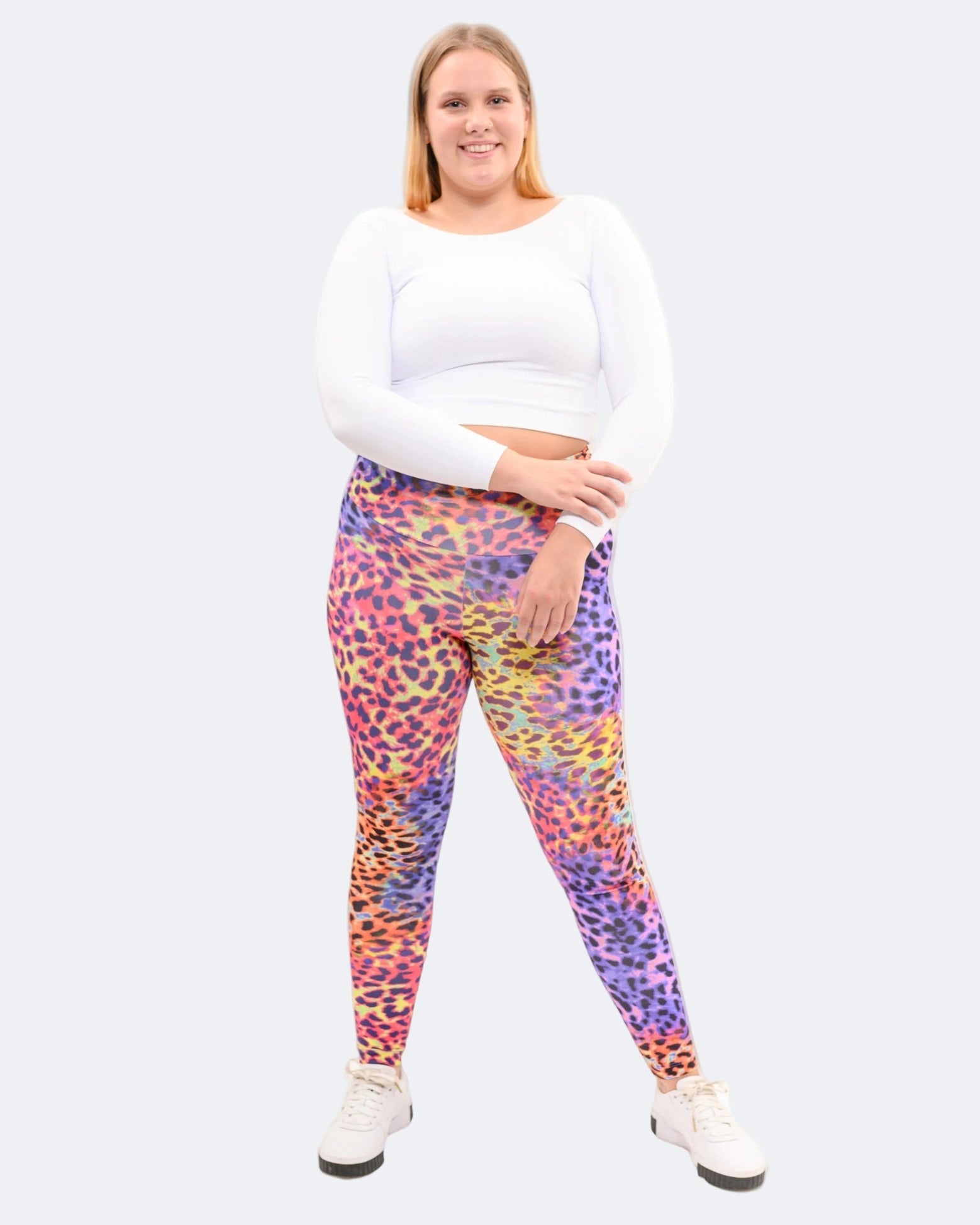 Model wearing colourful leopard patterned leggings and a white top on a cream background