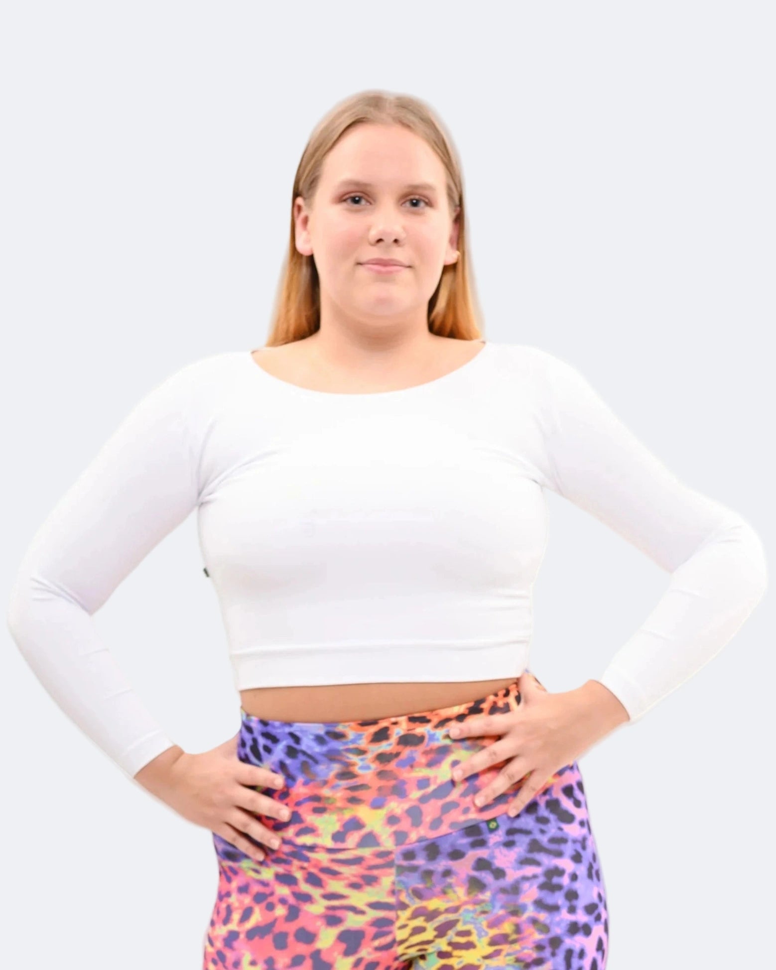Person wearing a white long-sleeve top and colorful skirt on a plain background