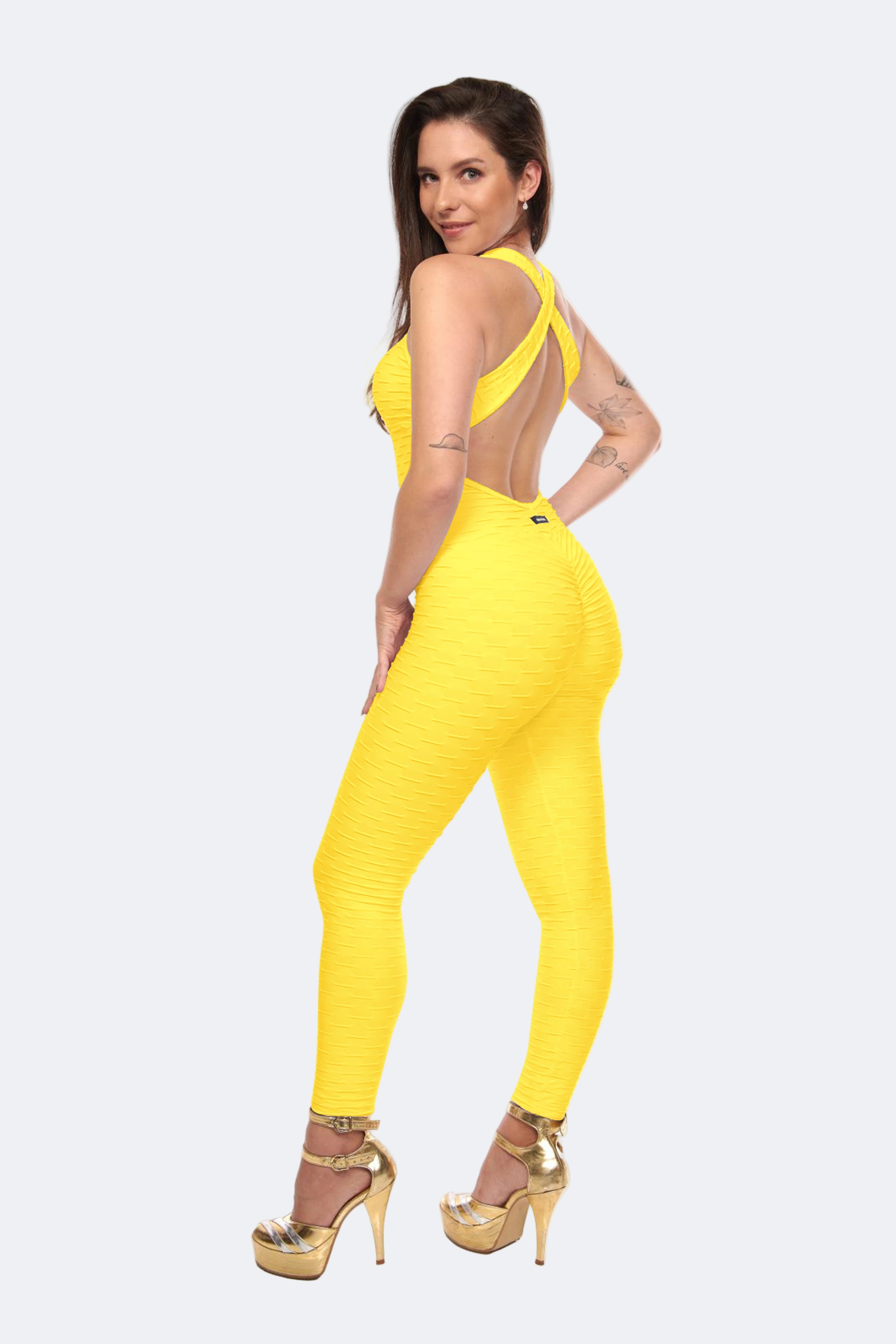 A woman posing in a yellow scrunch booty jumpsuit, which is designed to accentuate the figure, featuring a honeycomb texture and high waist.