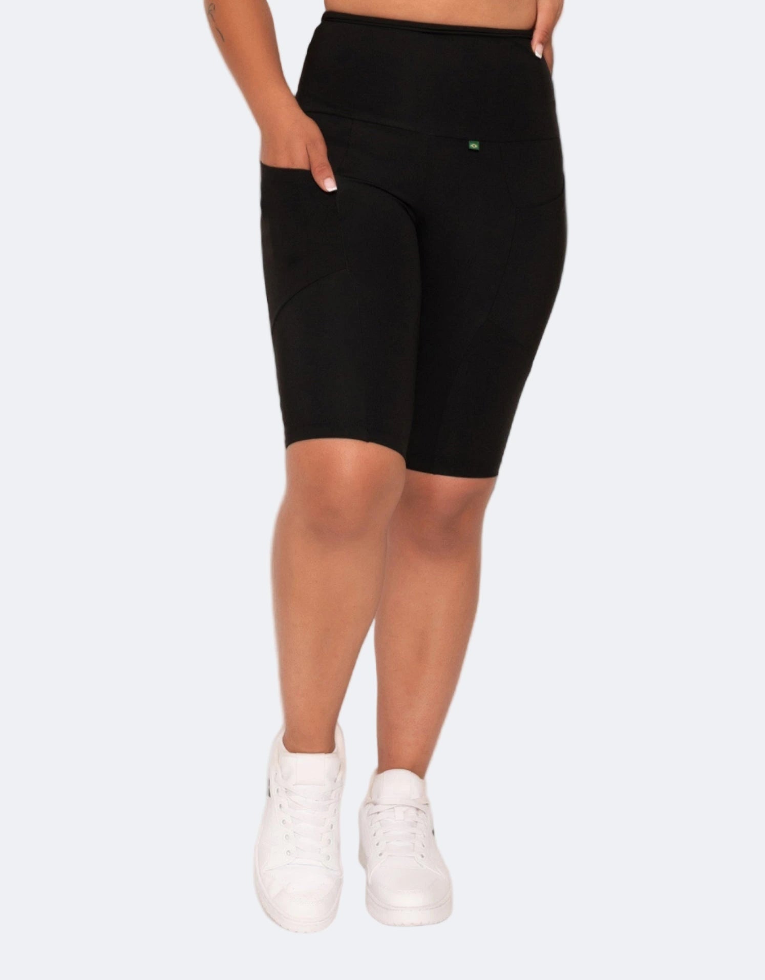 Woman wearing a black bike shorts with pocket on a light pink background