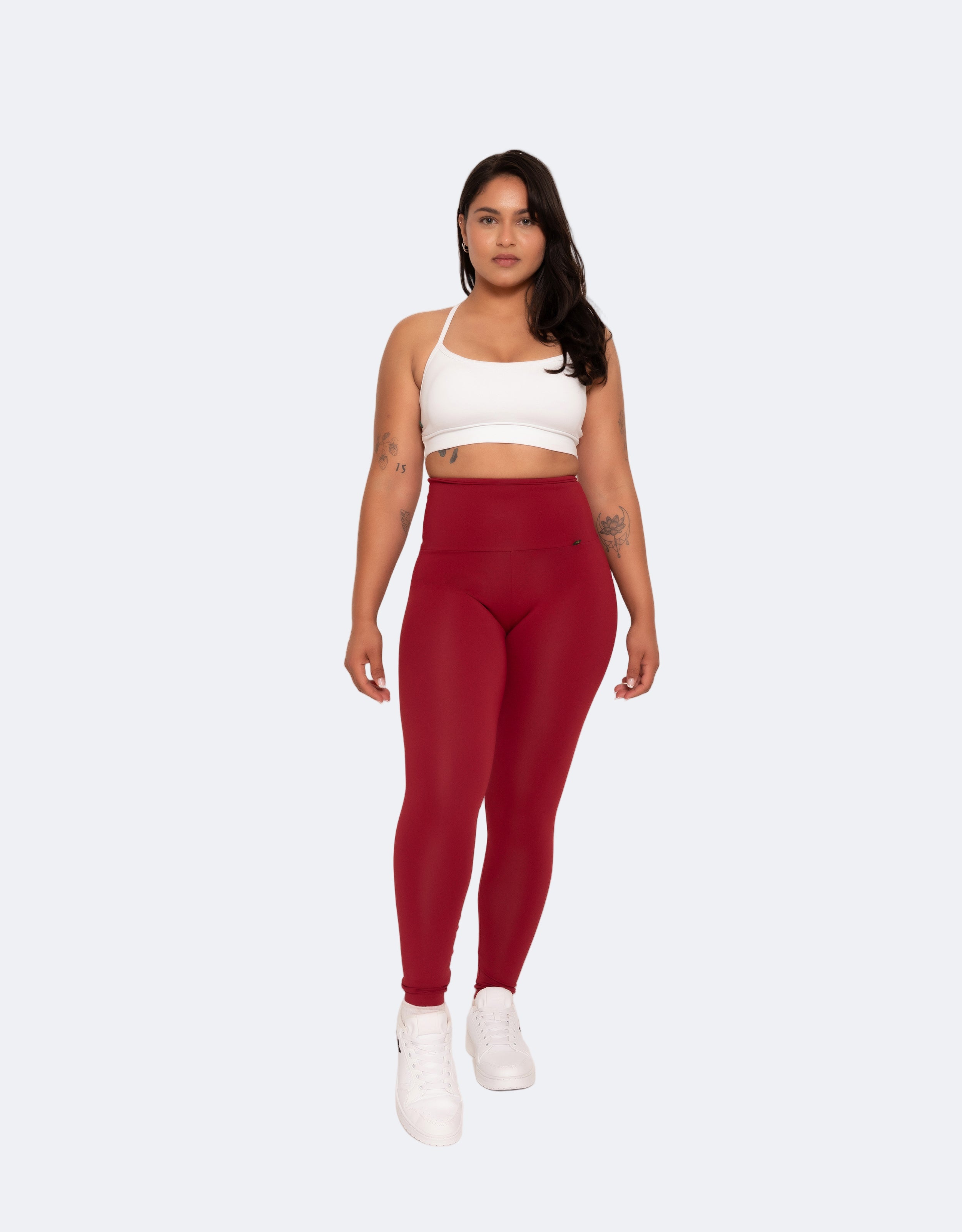 A model wearing high-waisted full-length red leggings with a white sports crop top.