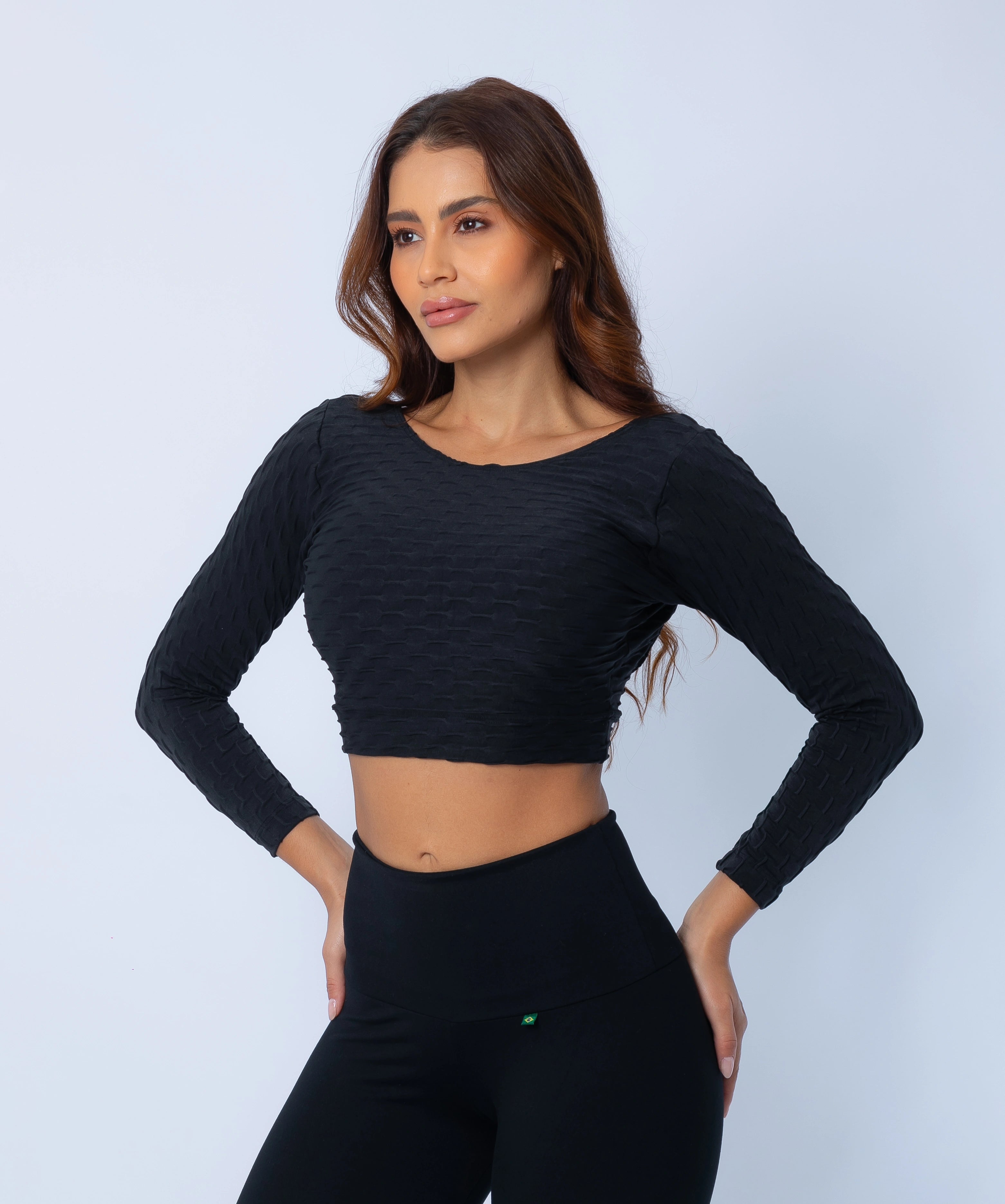Woman wearing a black long-sleeve crop top and leggings on a light gray background
