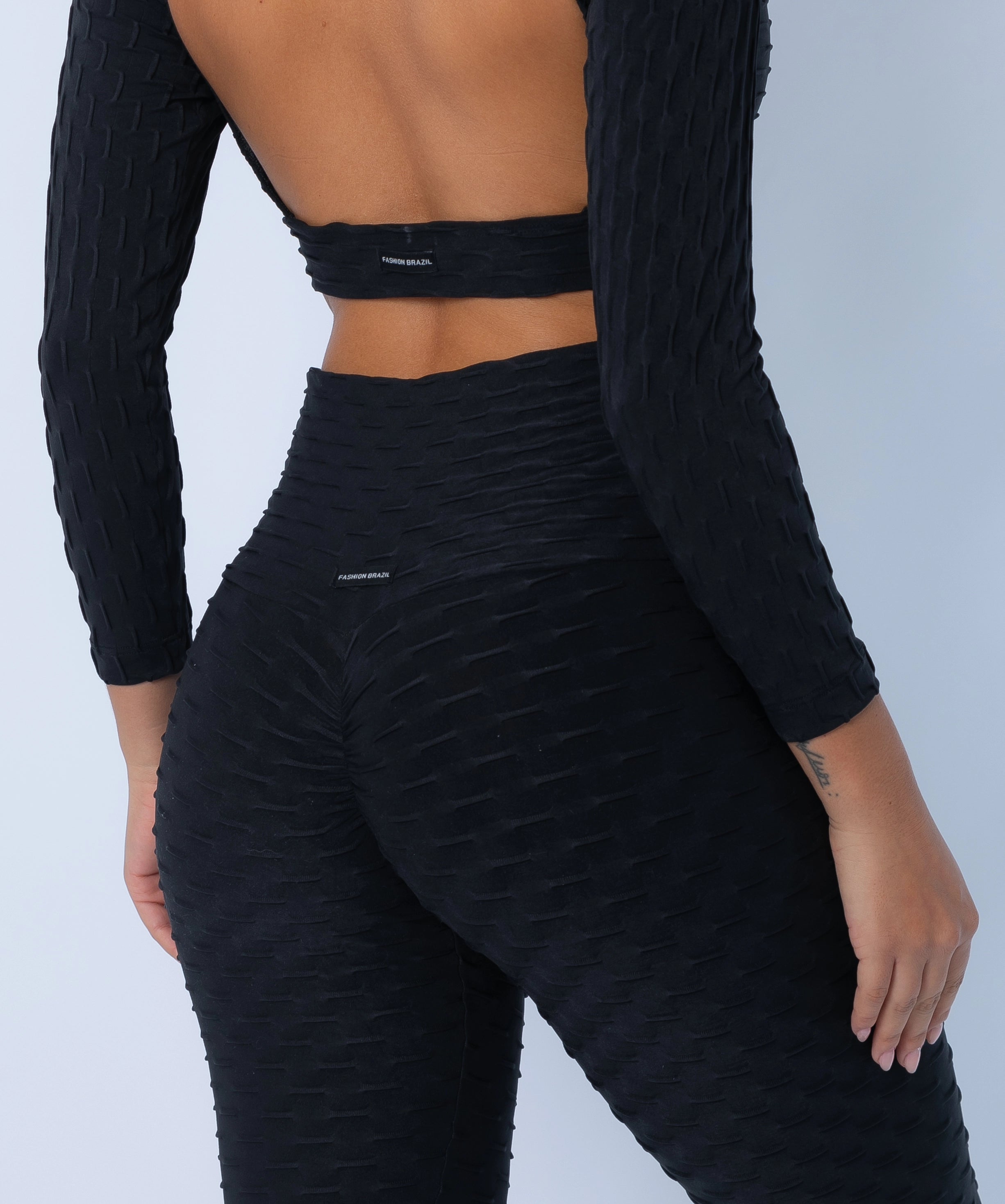 Fashion Brazil Luna Zero Flaws Scrunch Booty Leggings, close-up view highlighting scrunch-back seam for Brazilian Butt Lift effect in black textured fabric.
