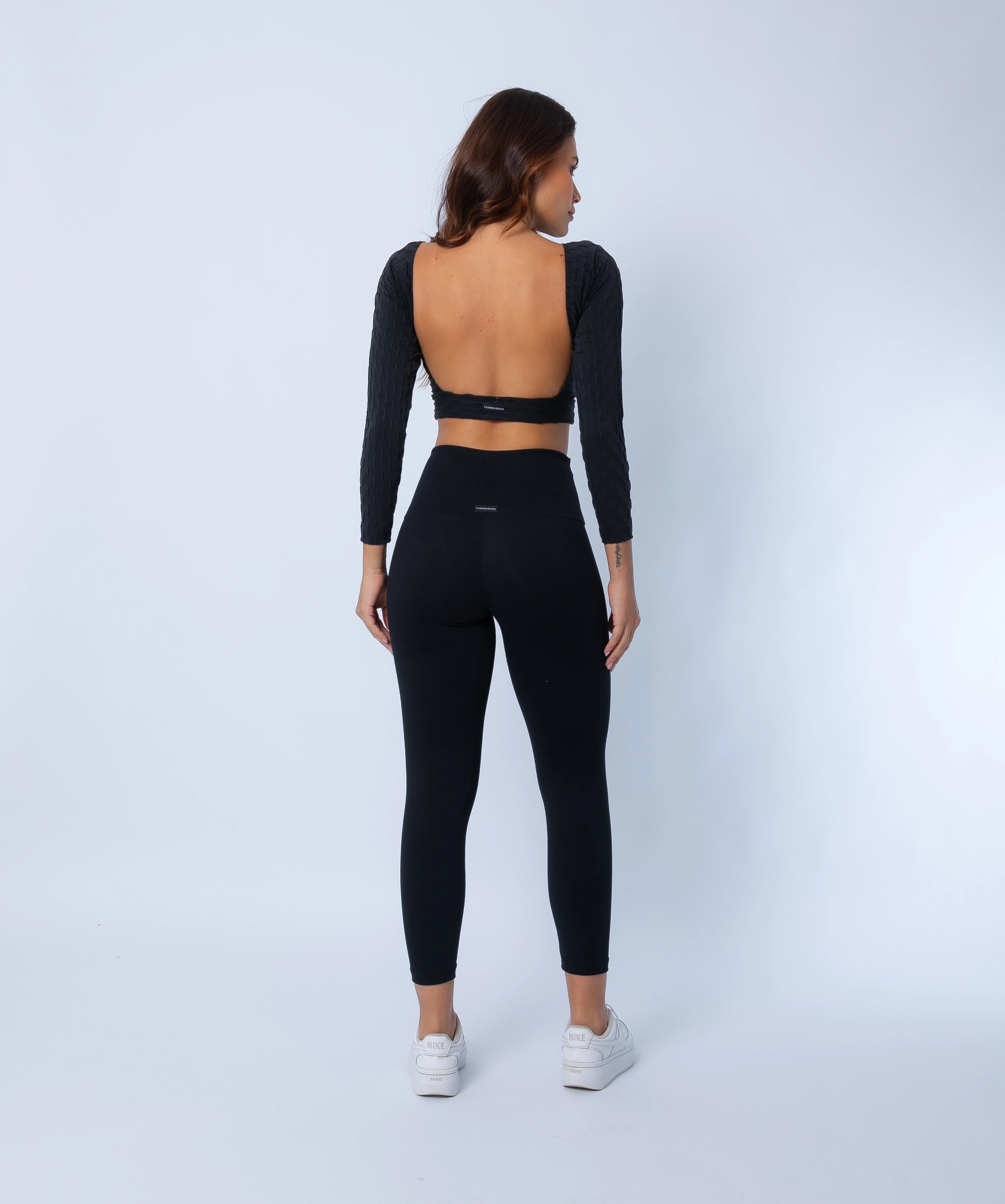 Back view showing 7/8 sculpting high waisted  and high compression legging and open-back top in black zero flaws textured fabric