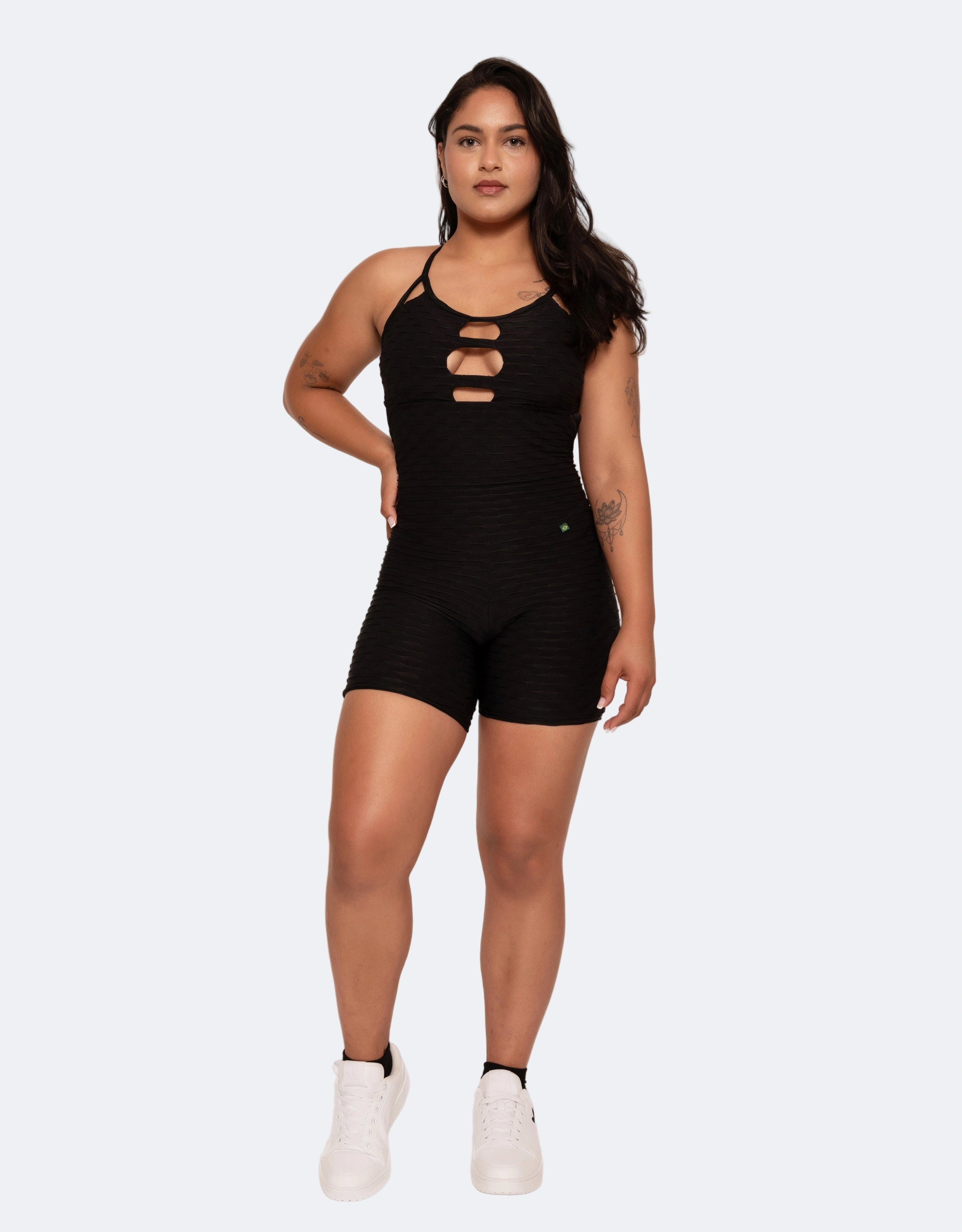 Woman wearing a black romper with cut-out details on a white background