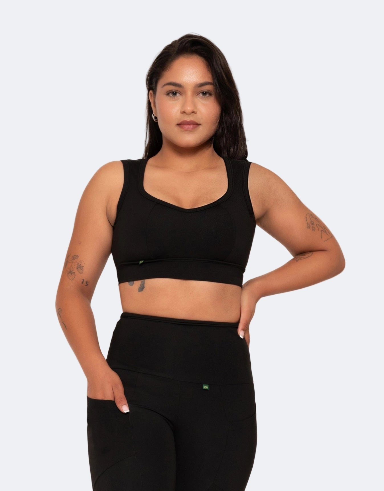 Woman wearing a black sports bra and leggings on a light gray background
