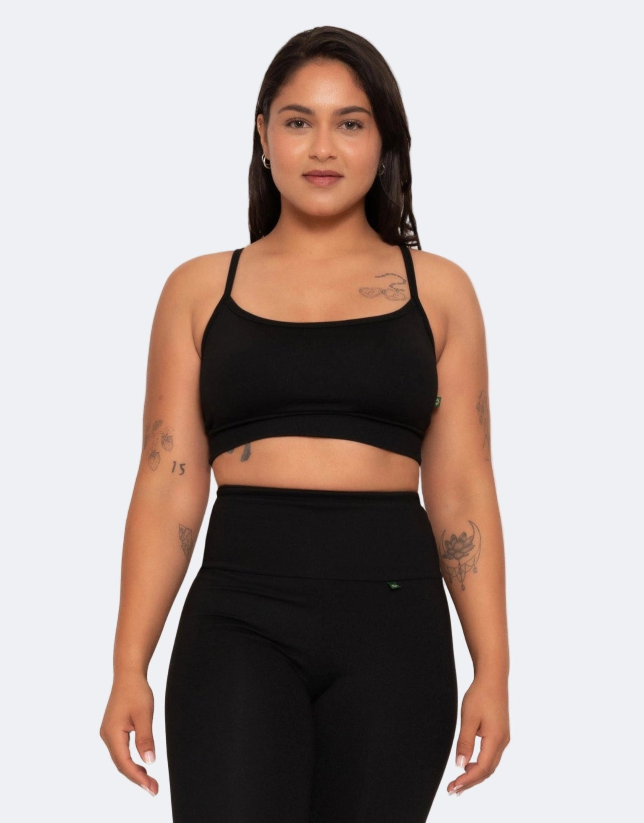 Woman wearing a black sports bra and leggings on a white background