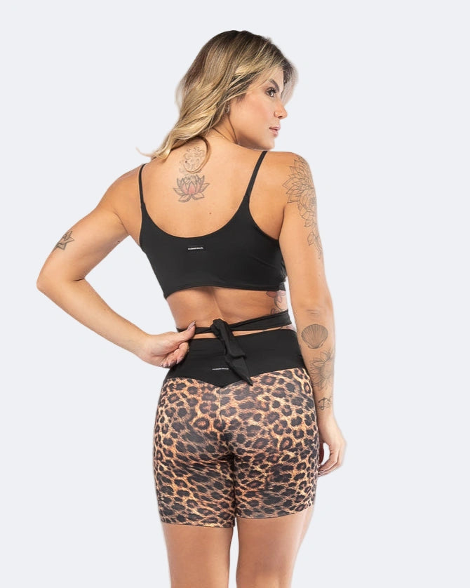Woman wearing a black sports bra and leopard print shorts on a white background