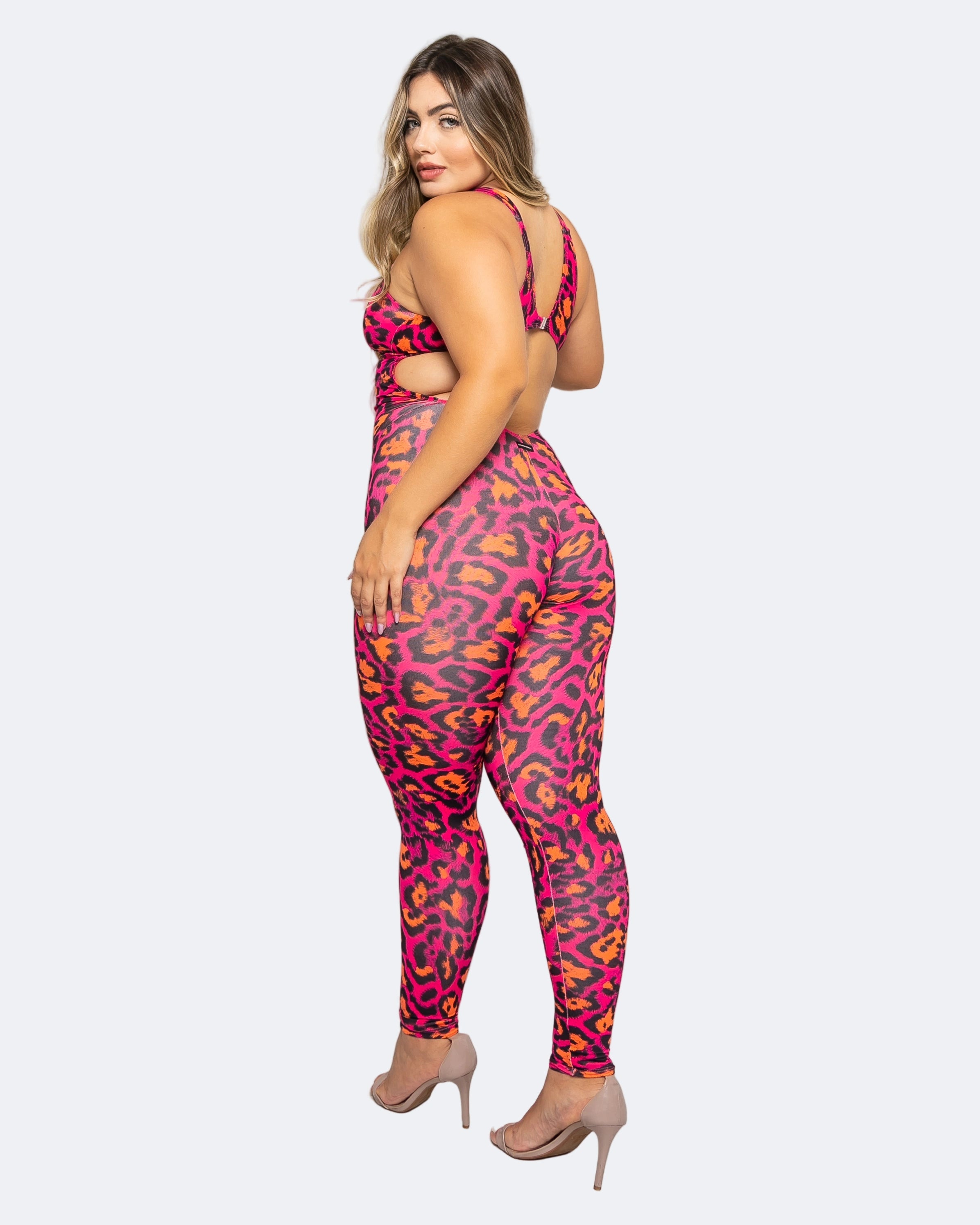 A model wearing a pink leopard print full-length jumpsuit with a medium-high waistband, designed for dancewear and performance.