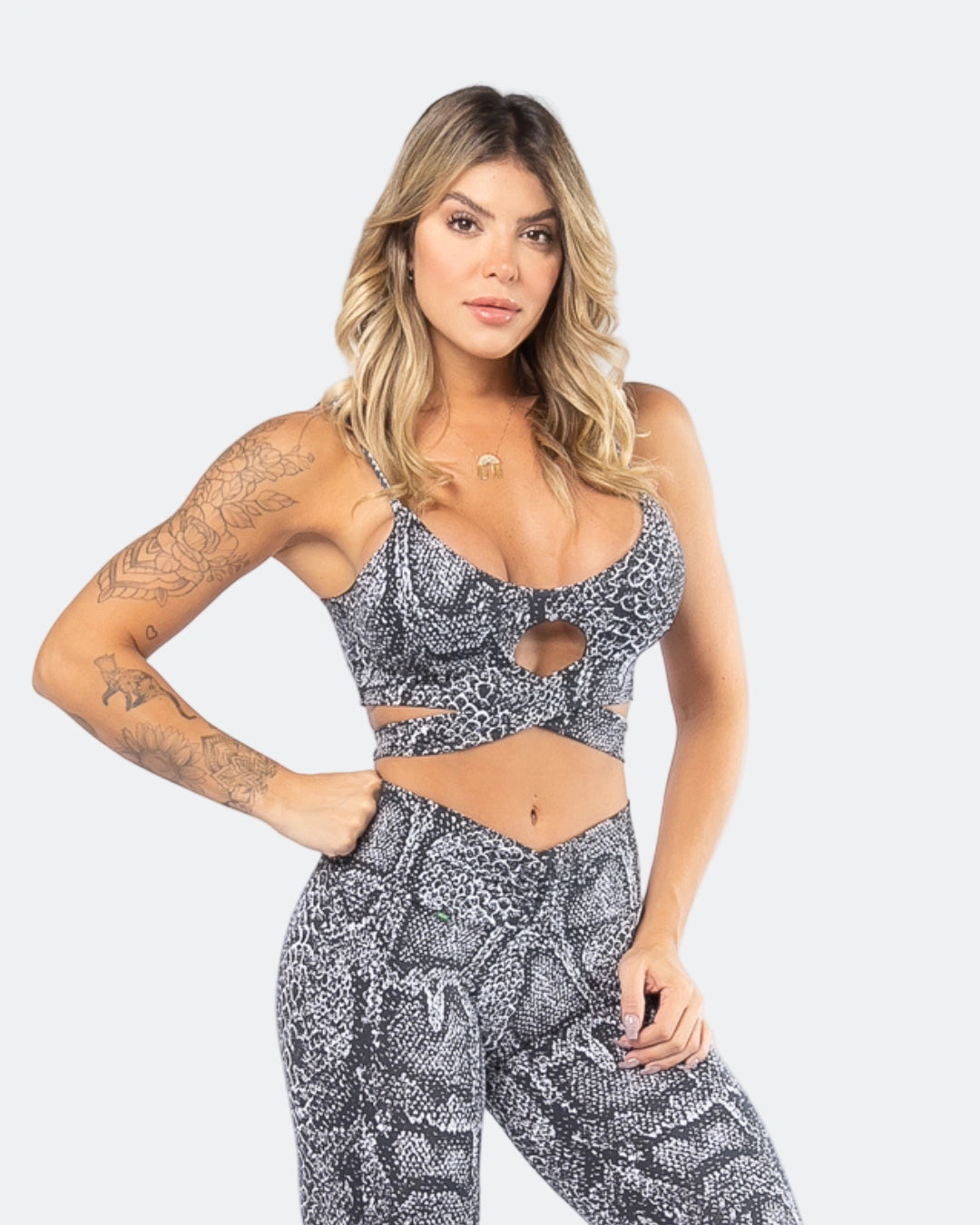 A woman wearing aPython Print Tie-Front Sports Bra in a matching set with leggings, the sports bra has a tie front feature and removable padding.