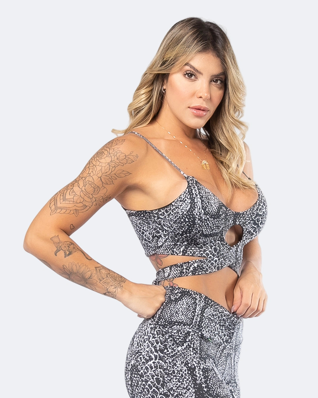 A woman wearing aPython Print Tie-Front Sports Bra in a matching set with leggings, the sports bra has a tie front feature and removable padding.