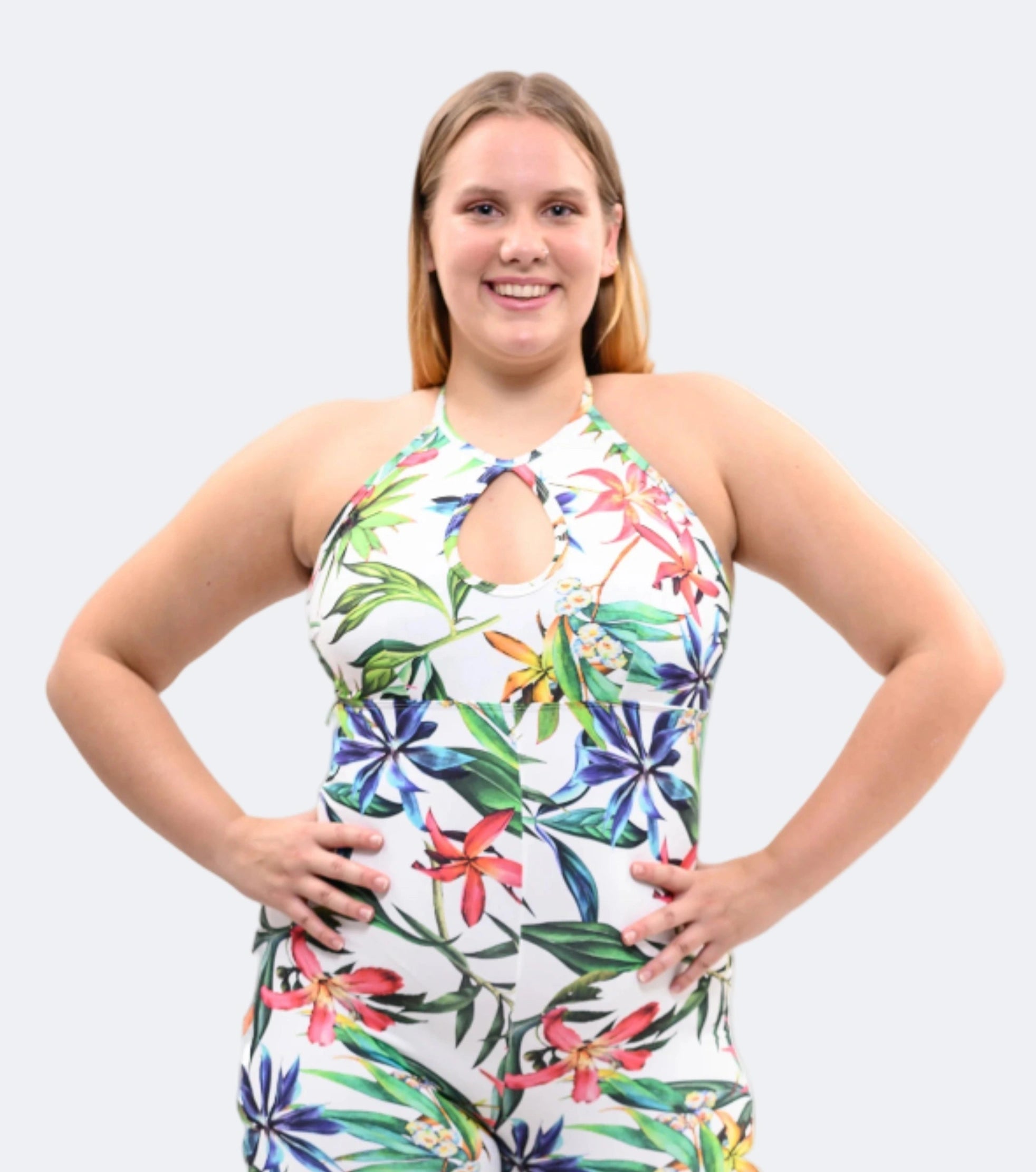 Woman wearing a colorful floral jumpsuit against a plain background