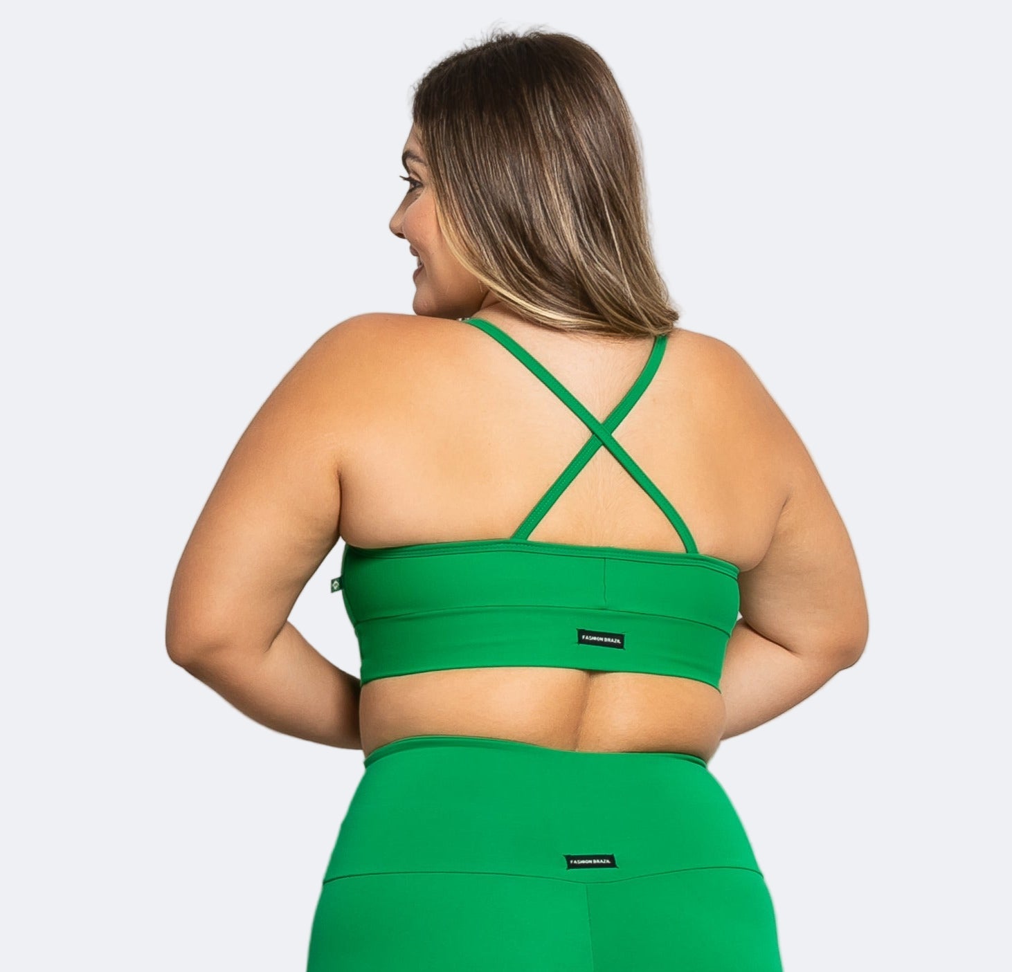 Woman wearing a green sports bra and leggings on a white background