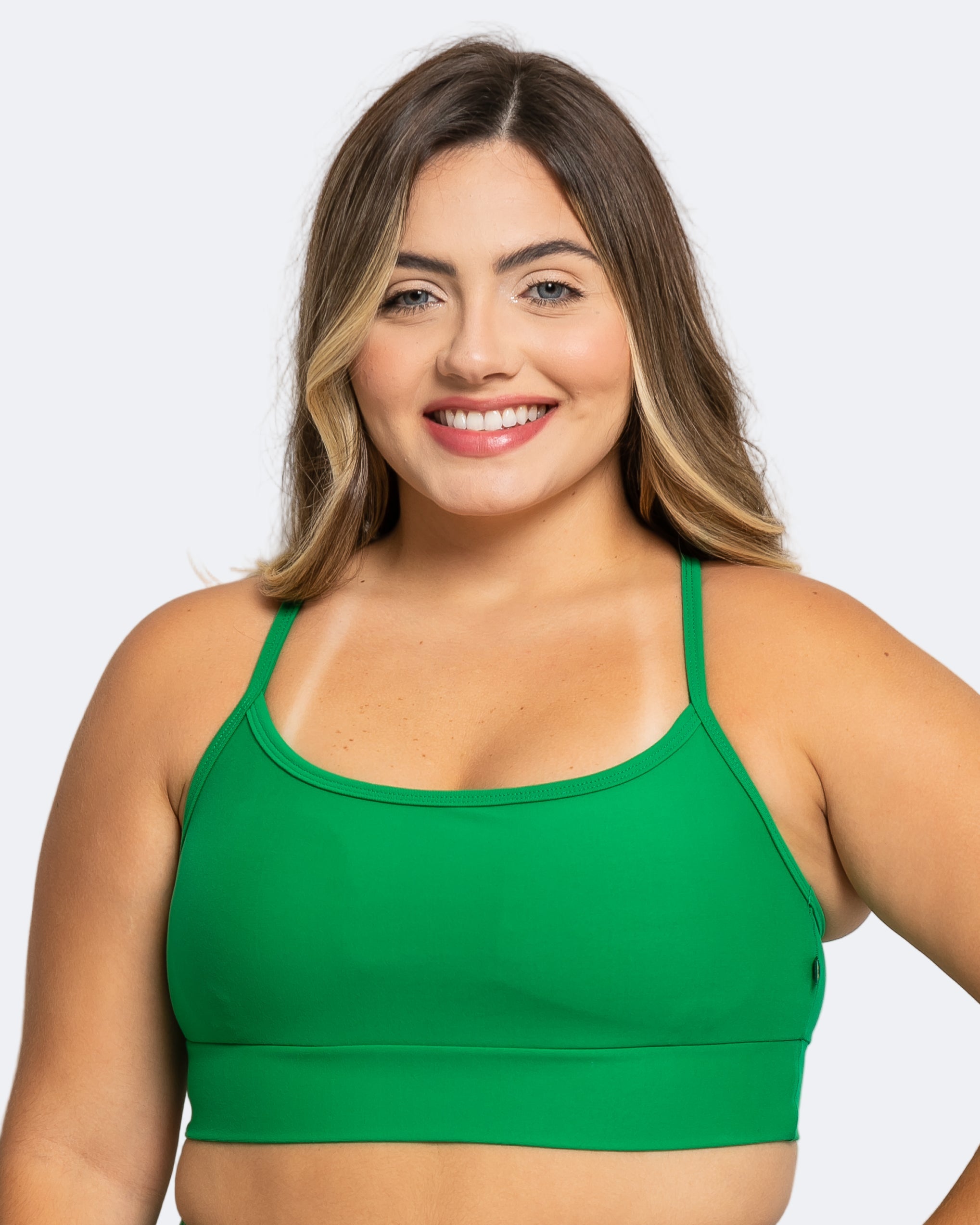 Woman wearing a green sports bra against a white background